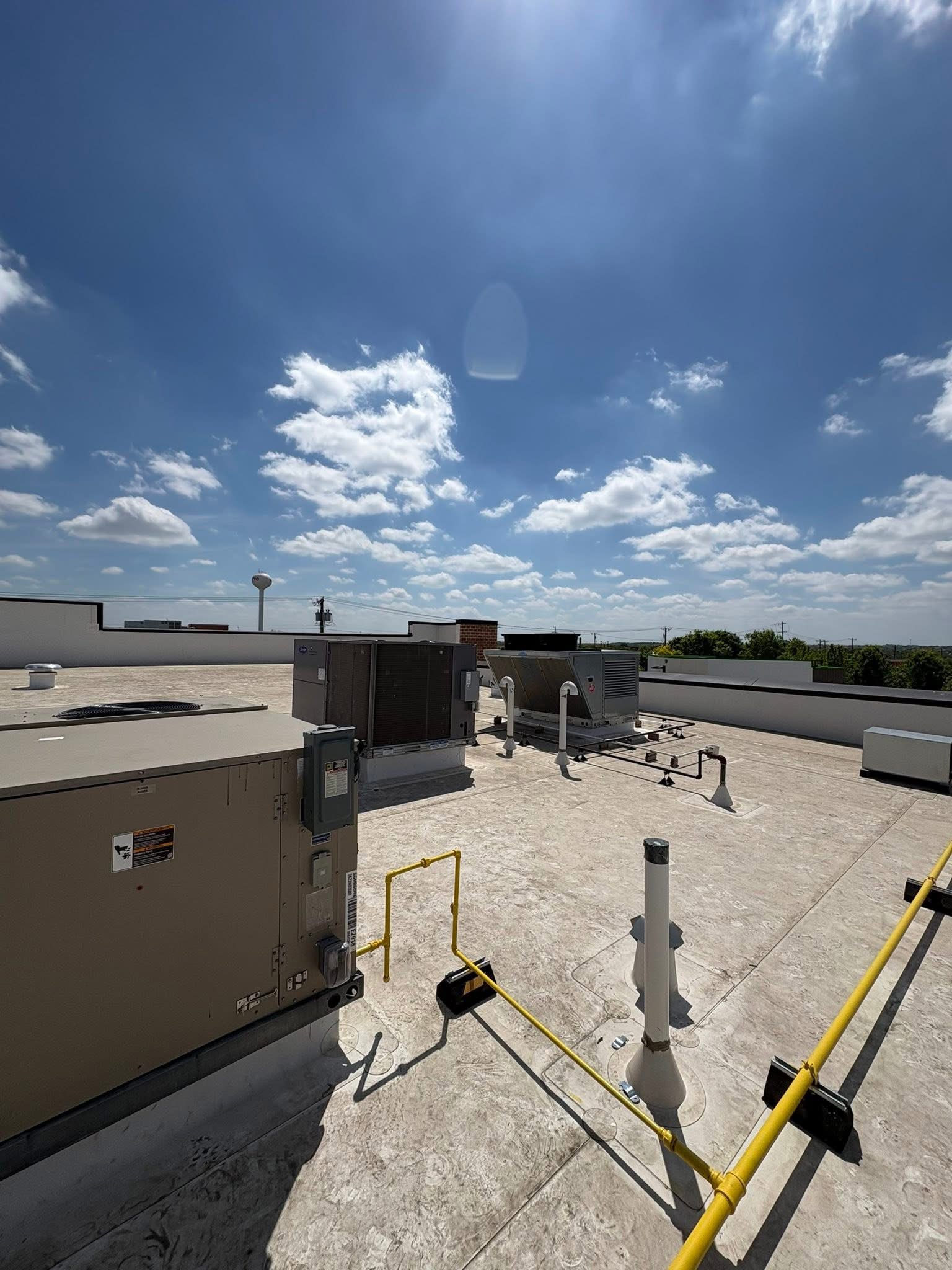 Commercial flat roof inspection view with HVAC units under a blue Texas sky